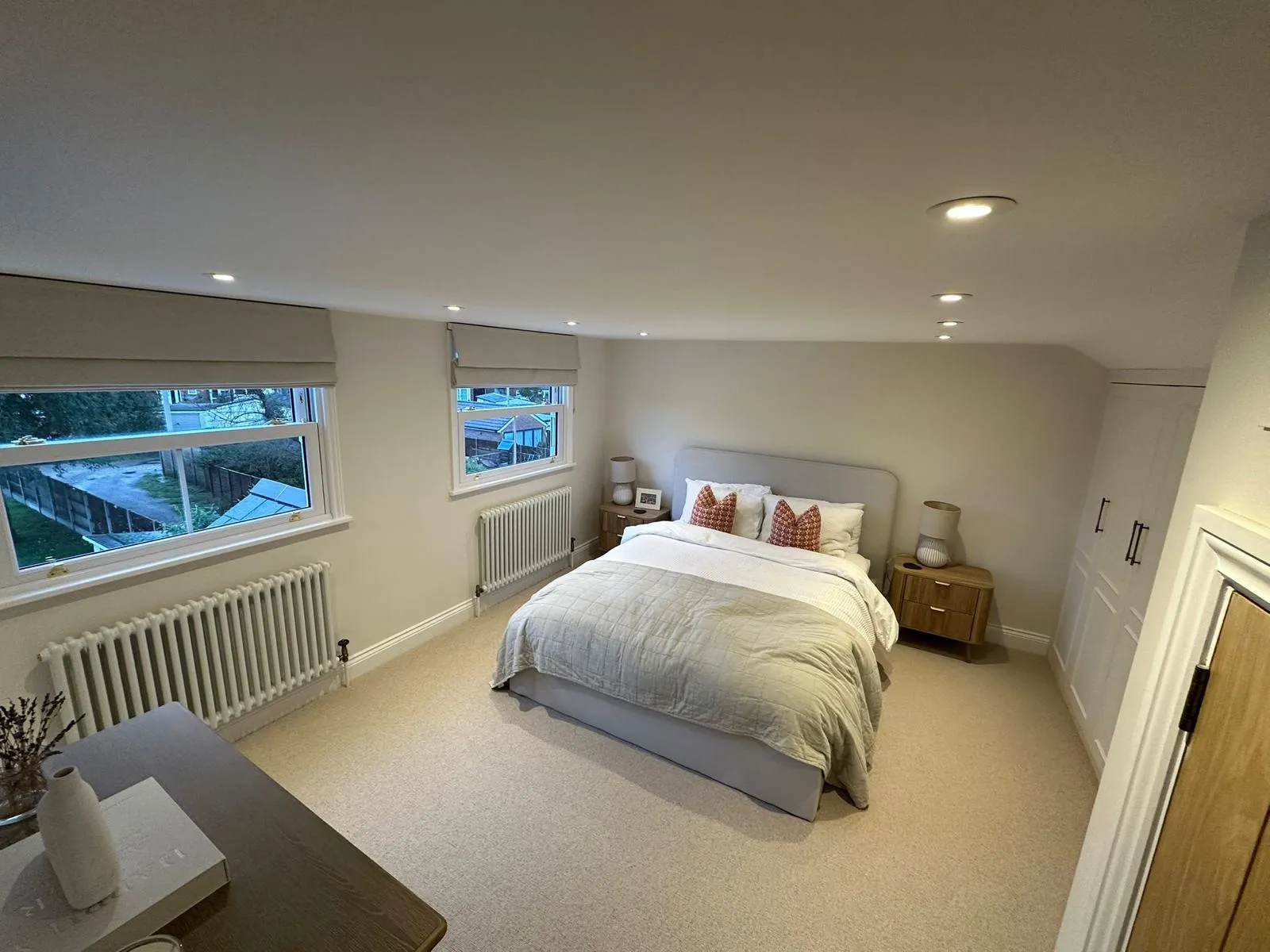 Spacious loft bedroom with upholstered bed and windows