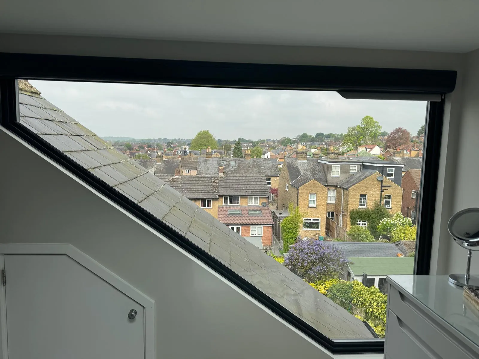 Custom angled window in loft space with rooftop view